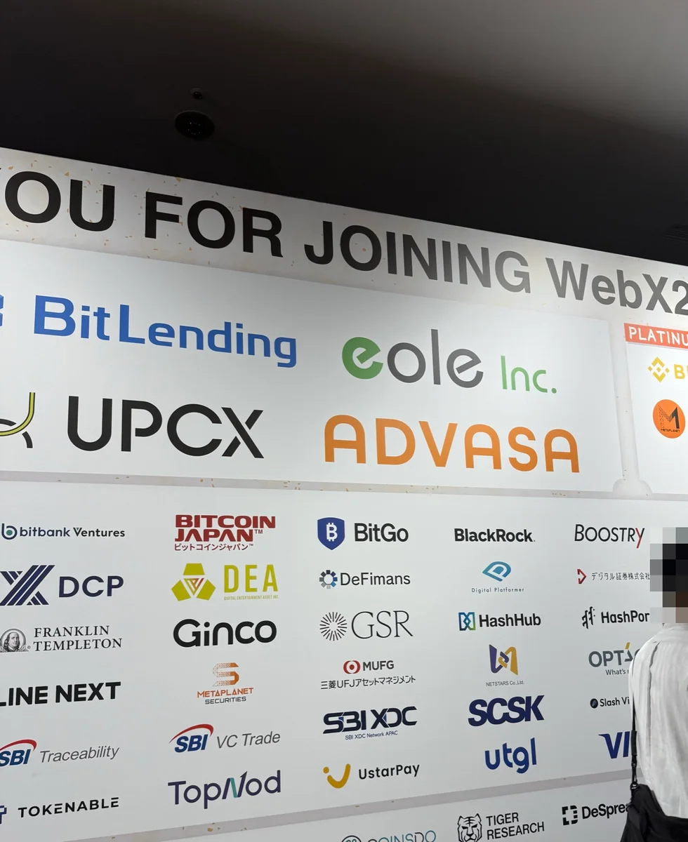 WebX 2026会場のスポンサー掲示。イオレのeole Inc.ロゴが大きく掲載され、右端の人物はモザイク加工済み