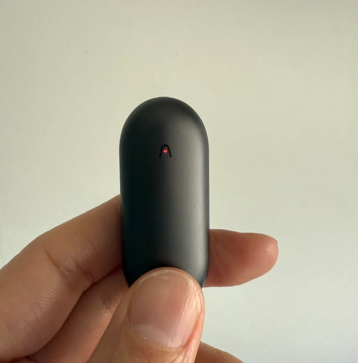 手に持った黒いPlaud NotePin。録音中を示す赤いランプが点灯している。